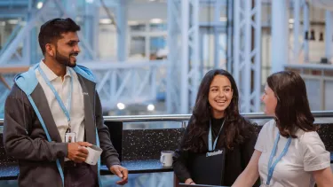 tre personer som ler och pratar i kontorslandskap