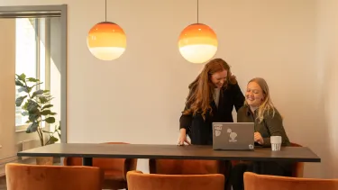 Två personer som skrattar och tittar på en bärbar dator.