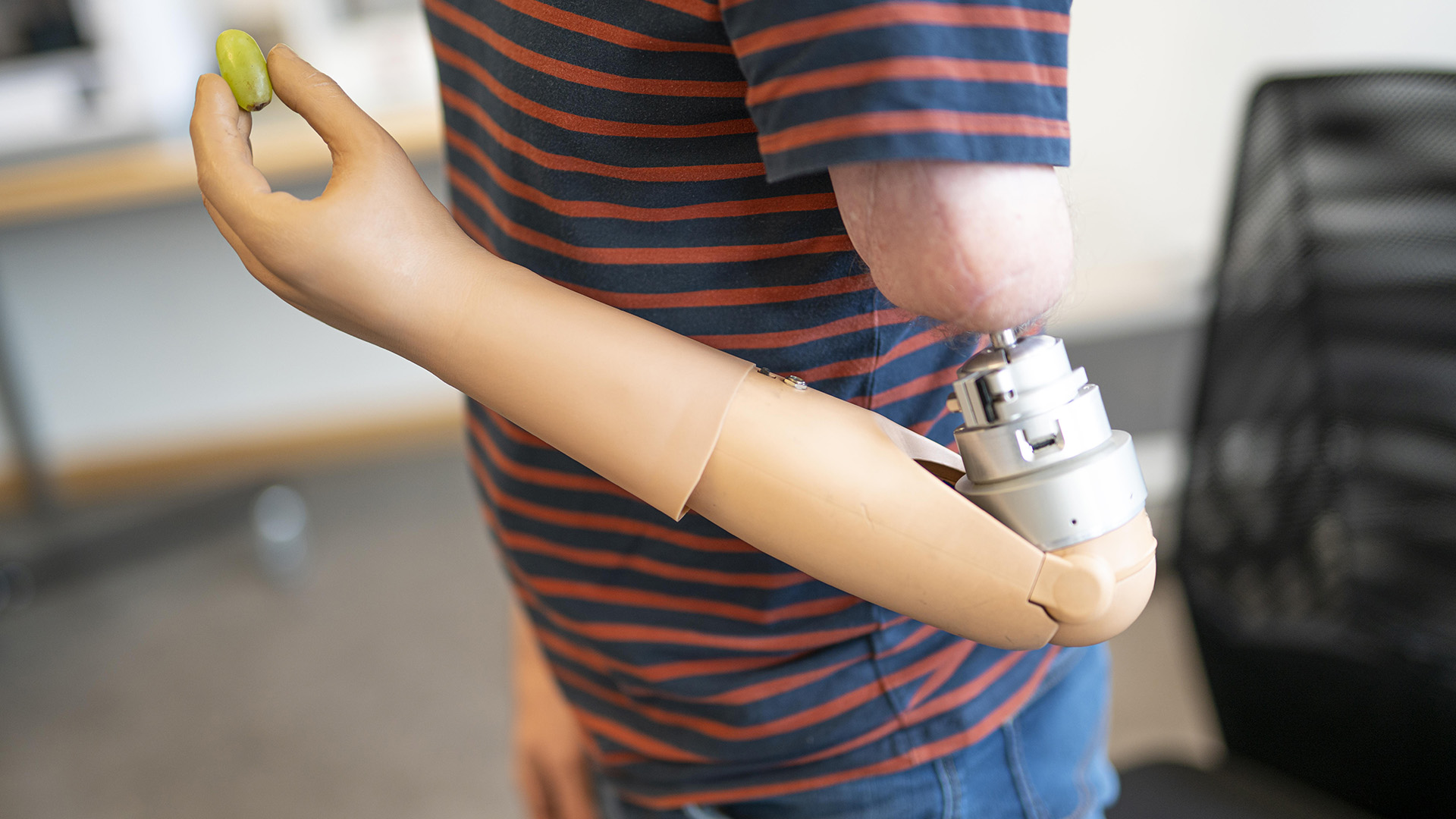 En person med armprotes som håller i en vindruva