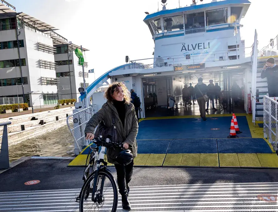 Kvinna går med cykel från färjan till Lindholmen