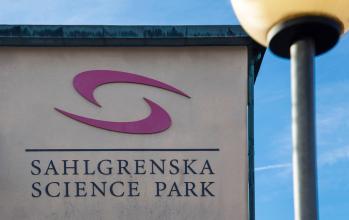 Närbild på en skylt med Sahlgrenska Science park skrivet på mot bakgrund av blå himmel och en lyktstolpe i förgrunden